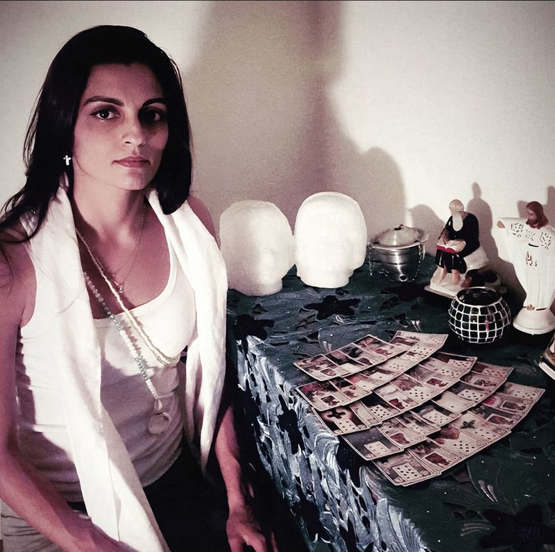 Mãe Estella ao lado de sua mesa de atendimento espiritual com cartas de tarô